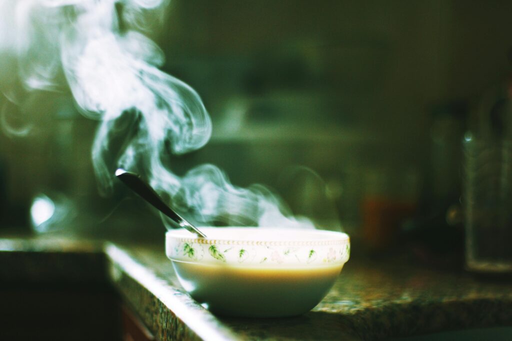 A steaming bowl of soup sits on a kitchen counter, emitting warm wafts into the air.