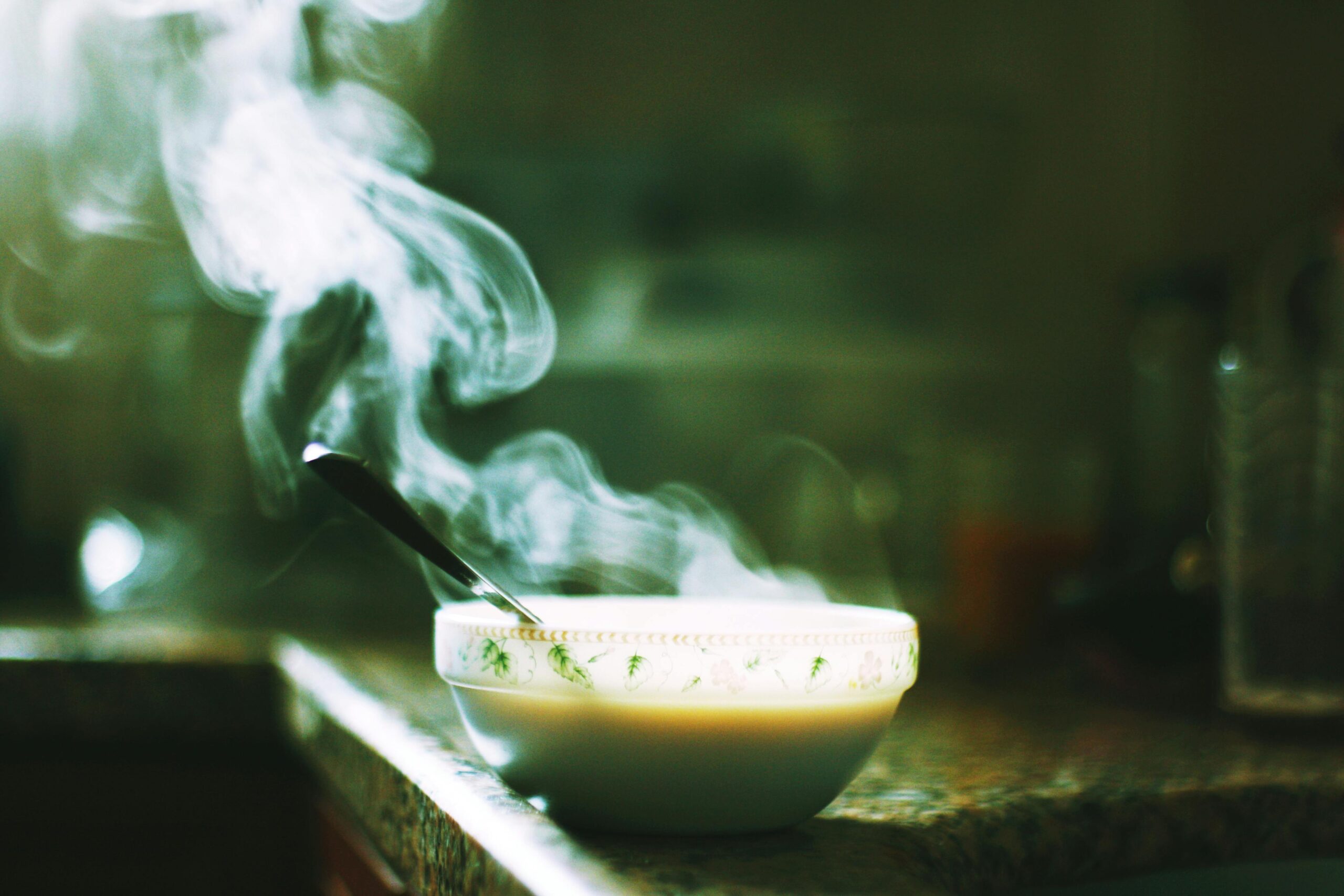 A steaming bowl of soup sits on a kitchen counter, emitting warm wafts into the air.